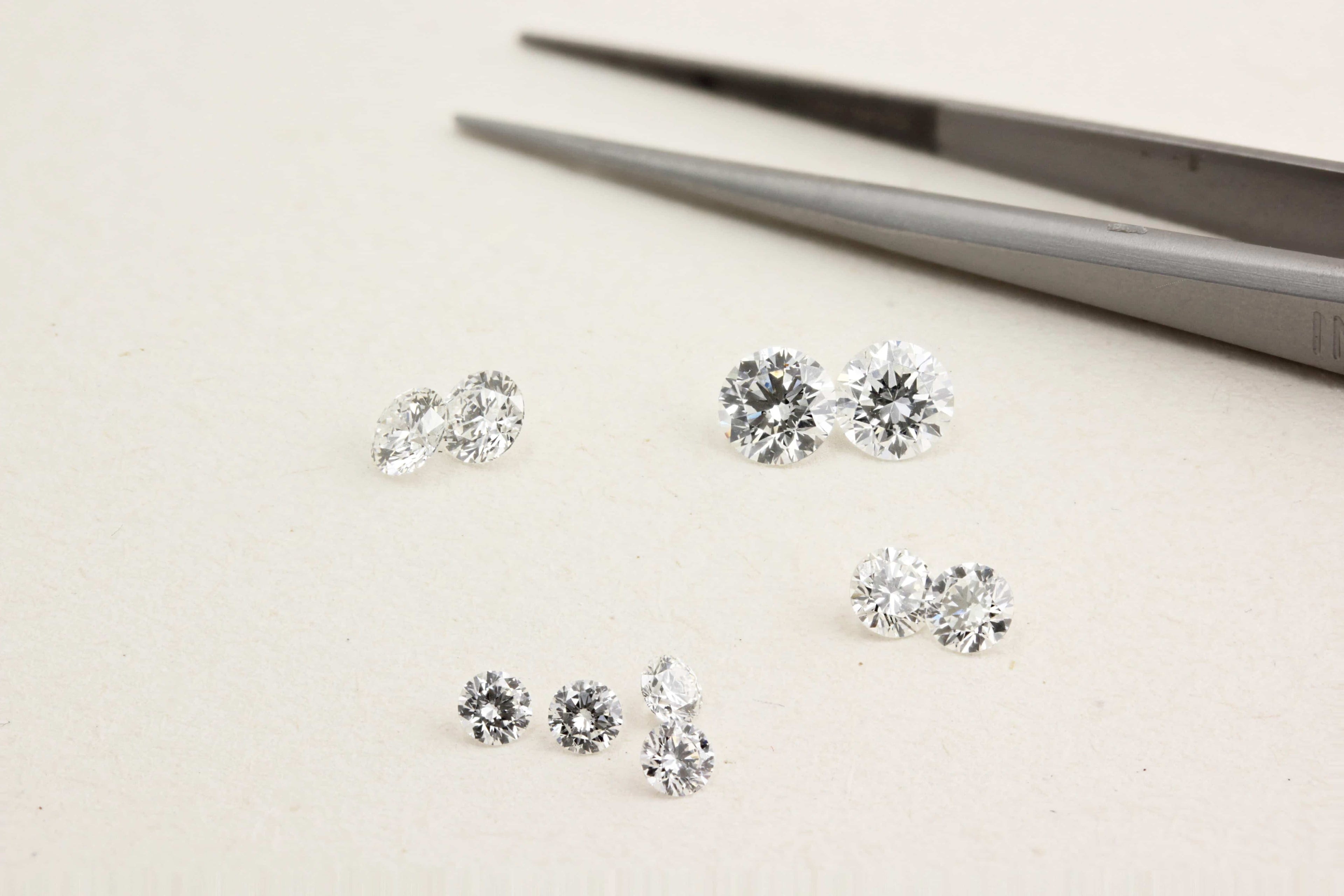 Diamond earrings on a light surface with tweezers