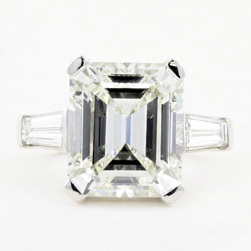 Emerald cut diamond ring with tapered baguettes on a white background