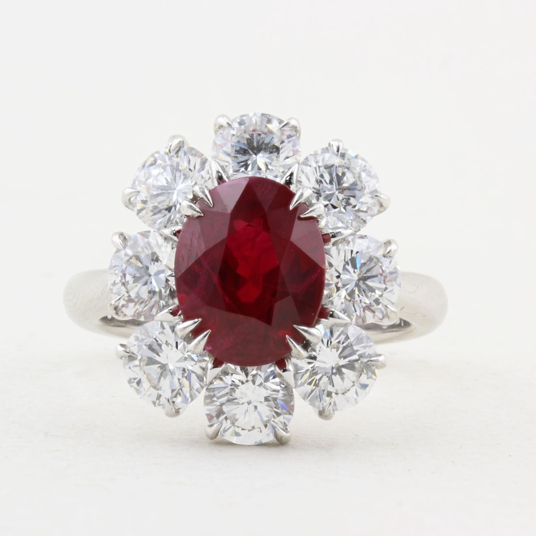 Ring with a vibrant red ruby surrounded by diamonds on a white background