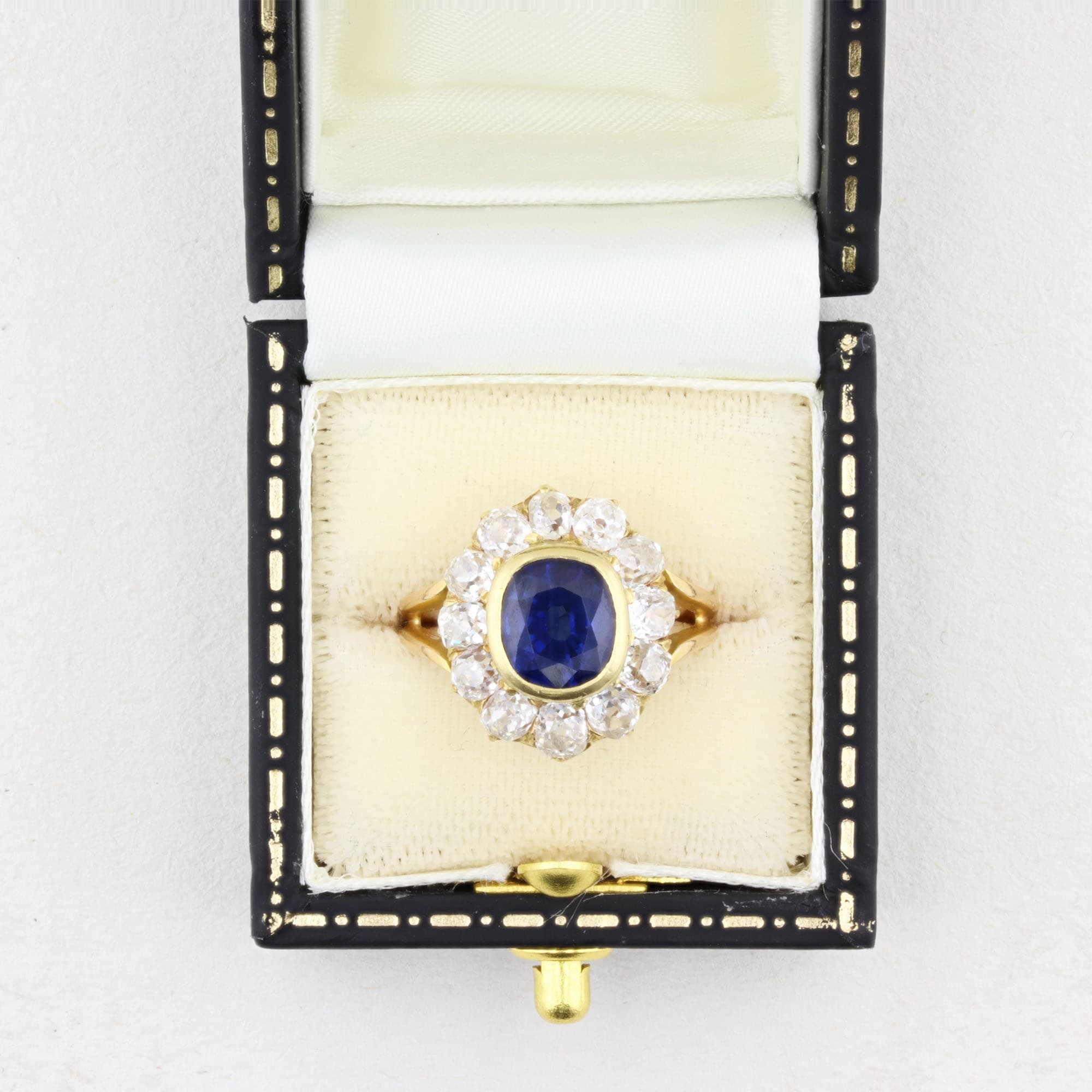 Gold ring with a blue gemstone in a decorative box on a white background