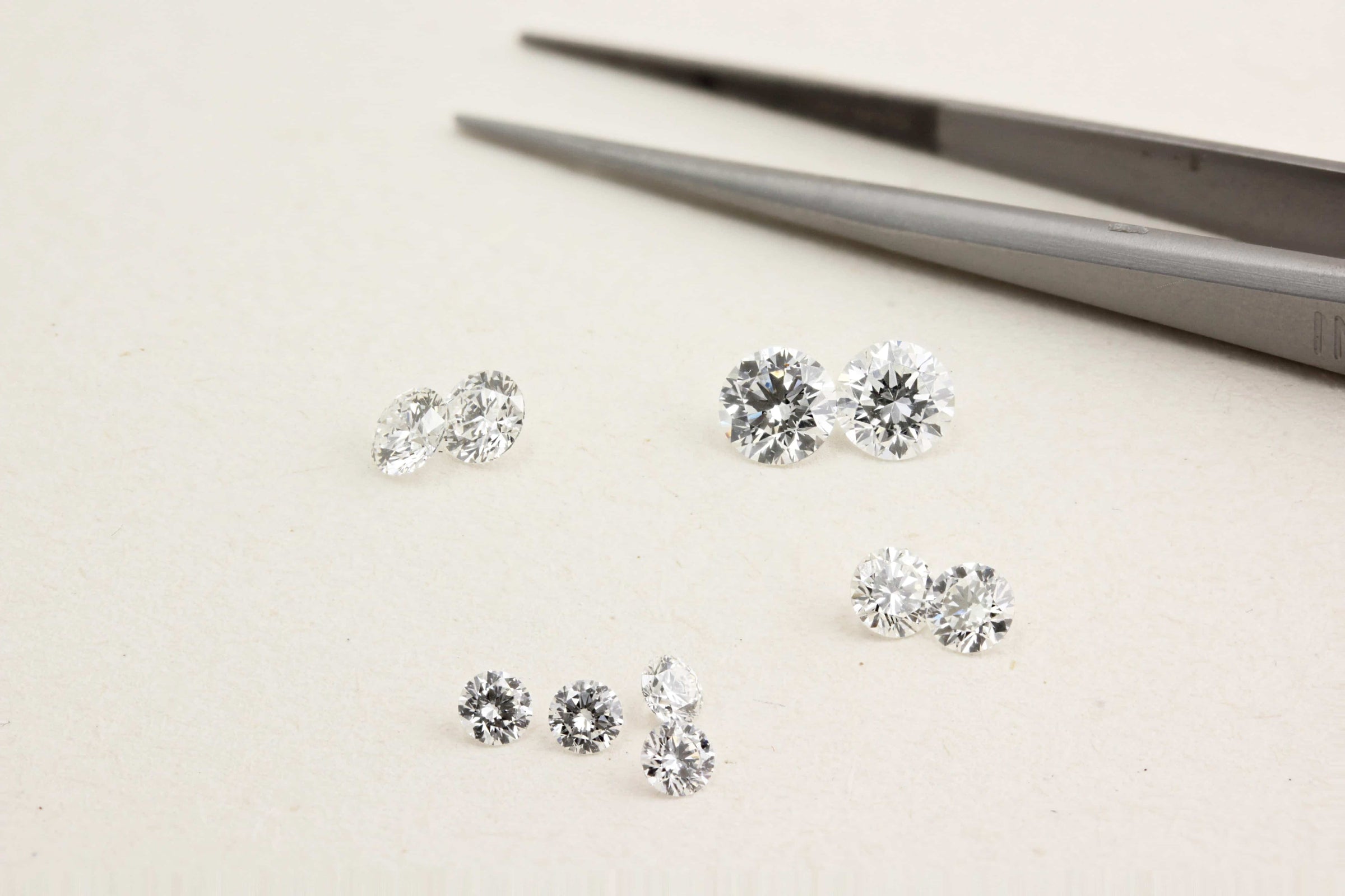 Diamond earrings on a light surface with tweezers