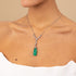 Necklace with a green Colombian emerald pendant worn by a person on a beige background