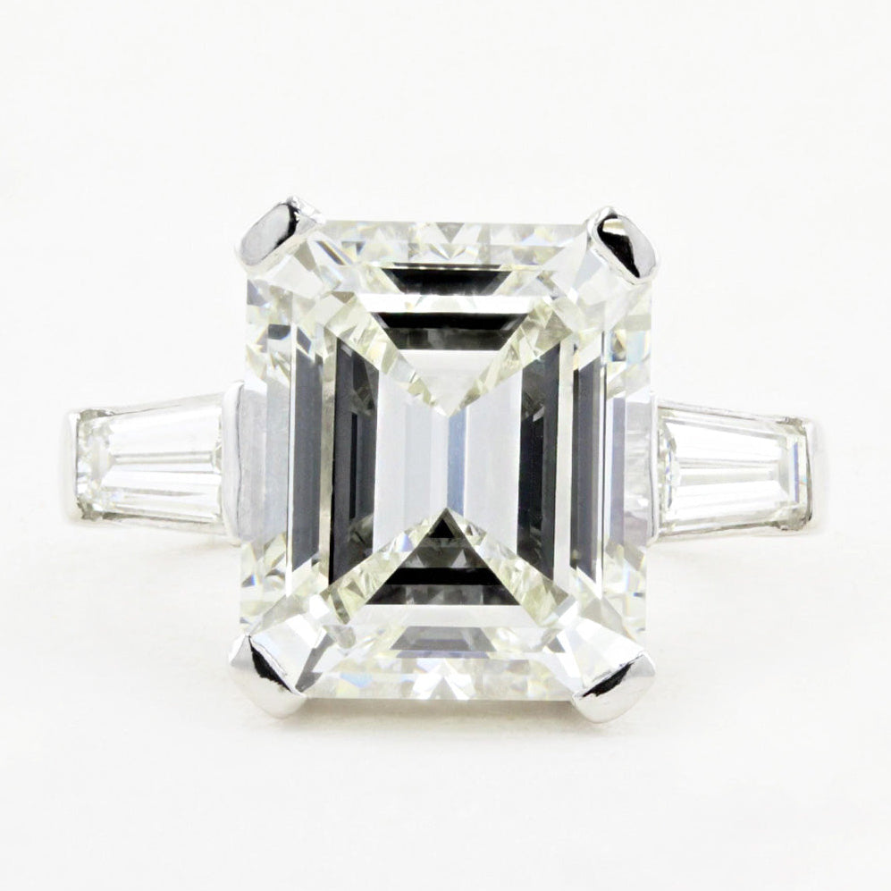 Emerald cut diamond ring with tapered baguettes on a white background
