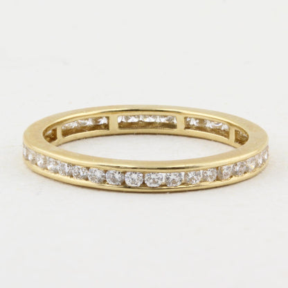 A yellow gold eternity ring featuring a continuous channel setting of round-cut diamonds on a plain white background.