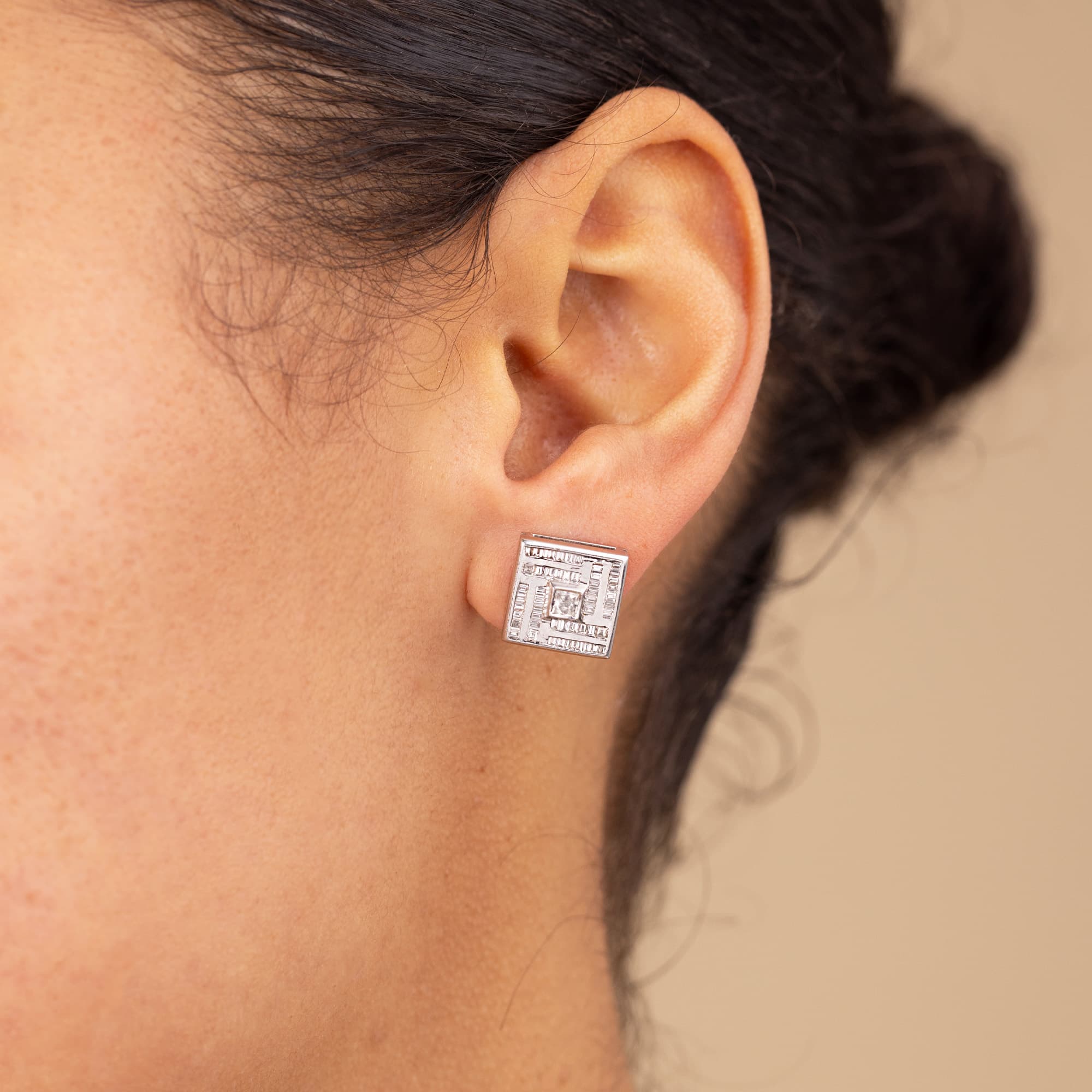 Square earring worn on an ear with a neutral background
