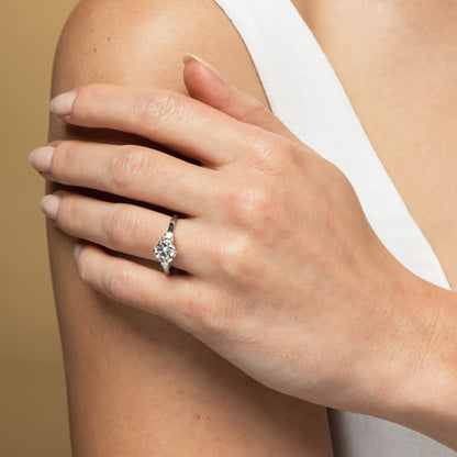 Hand wearing a diamond ring on a neutral background