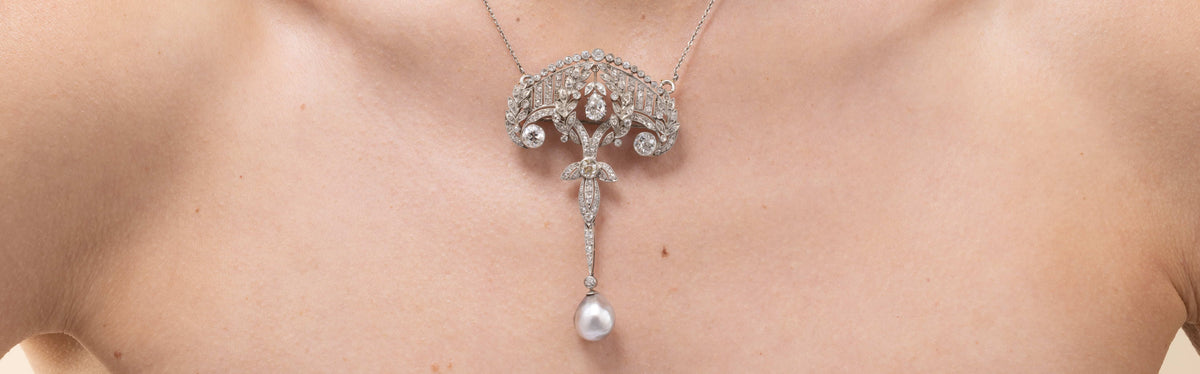 Delicate white gold, diamond and pearl necklace with a pendant on a person's neck